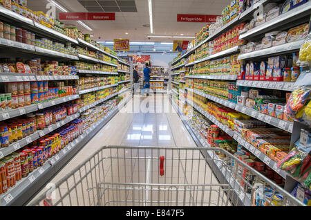 Warenkorb zwischen zwei waren Regale im Supermarkt. Stockfoto