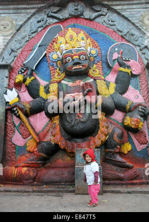 -Mädchen vor Kala Bhairab Figur in Kathmandu, Hanuman Dhoka Durbar Square, Nepal, Asien Stockfoto