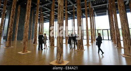 Berlin, Deutschland. 30. September 2014. Besucher zu Fuß zwischen den Baumstämmen im Erdgeschoss der neuen Nationalgalerie in Berlin, Deutschland, 30. September 2014 ausgestellt. Die Installation von berühmten britischen Architekten Dacid Chipperfield besteht aus 144 Baumstämme und ist ein Prolog für die Renovierung der Galerie von Chipperfield für 2015 geplant. Foto: STEPHANIE PILICK/DPA/Alamy Live-Nachrichten Stockfoto