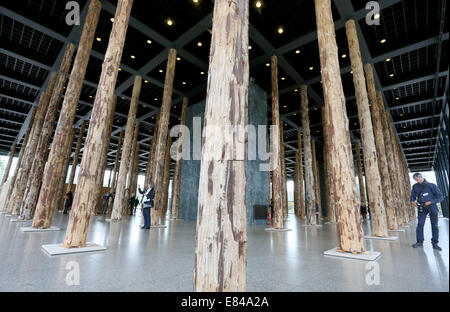 Berlin, Deutschland. 30. September 2014. Besucher zu Fuß zwischen den Baumstämmen im Erdgeschoss der neuen Nationalgalerie in Berlin, Deutschland, 30. September 2014 ausgestellt. Die Installation von berühmten britischen Architekten Dacid Chipperfield besteht aus 144 Baumstämme und ist ein Prolog für die Renovierung der Galerie von Chipperfield für 2015 geplant. Foto: STEPHANIE PILICK/DPA/Alamy Live-Nachrichten Stockfoto