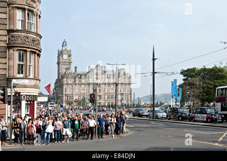 Menge von Fußgängern warten, um St David Strasse mit Princes Street, Edinburgh, und das Balmoral Hotel im Hintergrund Stockfoto
