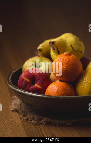 eine Obstschale beleuchtet durch schießen durch Regenschirm ein Holztisch Stockfoto