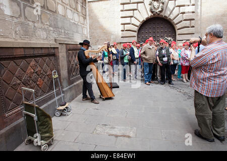 Gruppe von Touristen unterwegs anhören Harfe-Spieler in der Innenstadt von Barcelona in Katalonien, Spanien. Stockfoto