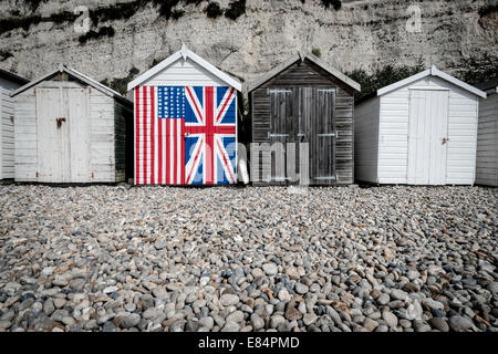 Eine Strandhütte, gemalt mit den britischen und amerikanischen Flaggen, stehend gegen ihren Nachbarn im tristen und schmucklosen. Stockfoto