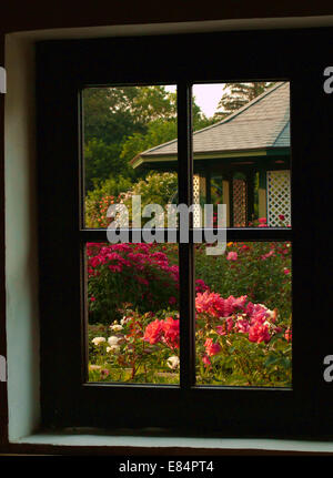 Blick aus einem inneren Fenster auf einen Garten und Pavillon Stockfoto