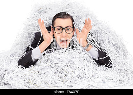 Erschrockenen Mann bedeckt in einem Haufen von Shredder Papier isoliert auf weißem Hintergrund Stockfoto