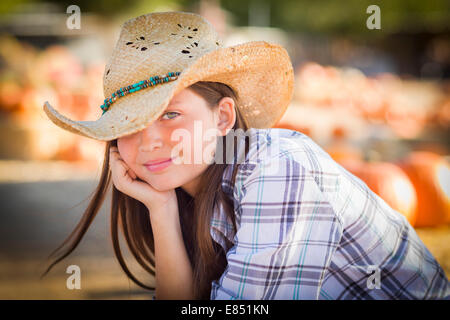 Ziemlich Preteen Mädchen tragen Cowboyhut Porträt im Kürbisbeet in rustikaler Umgebung. Stockfoto