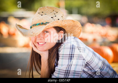 Ziemlich Preteen Mädchen tragen Cowboyhut Porträt im Kürbisbeet in rustikaler Umgebung. Stockfoto