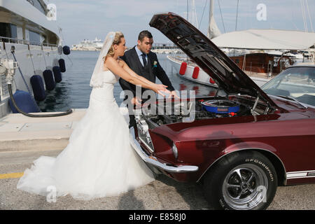 Braut und Bräutigam suchen nach einer Panne in einem Hafen in den Motorraum eines Ford Mustang Stockfoto