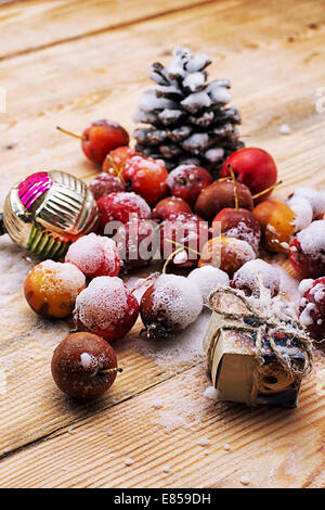 Schnee-bedeckten Früchte der Zwerg Äpfel und Weihnachtsschmuck Stockfoto