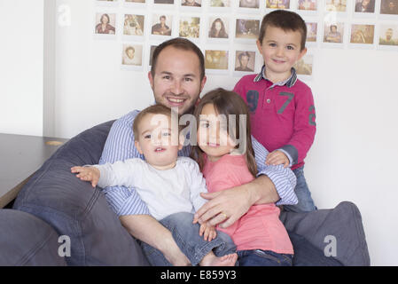 Vater und Kinder sitzen zusammen auf Sofa, Porträt Stockfoto