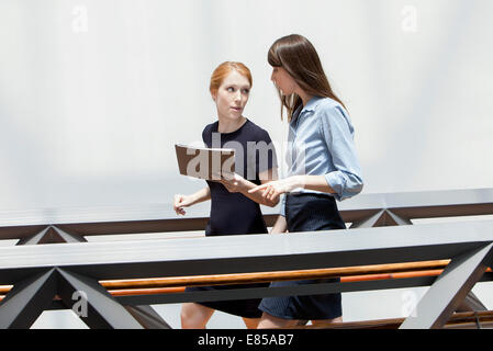 Geschäftsfrauen zu Fuß und im Korridor miteinander reden Stockfoto