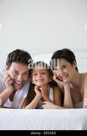 Eltern und Tochter gemeinsam auf Bett liegend, portrait Stockfoto