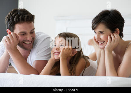 Eltern und Tochter gemeinsam auf Bett liegend, portrait Stockfoto