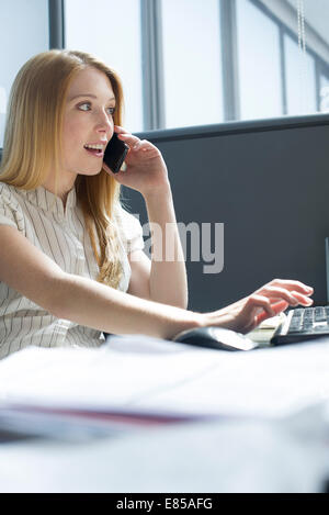 Kaufmännische Angestellte von der Arbeit durch persönliche Anruf abgelenkt Stockfoto