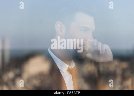 Geschäftsmann, reden über Handy, angesehen durch Fenster Stockfoto