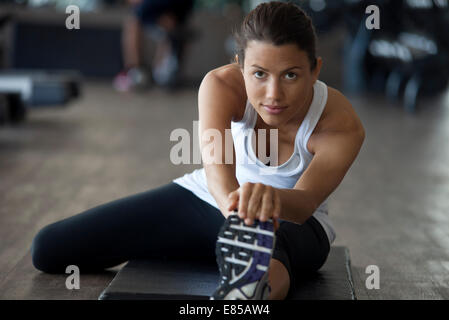 Frau in Turnhalle Aufwärmen mit Bein Strecken Stockfoto