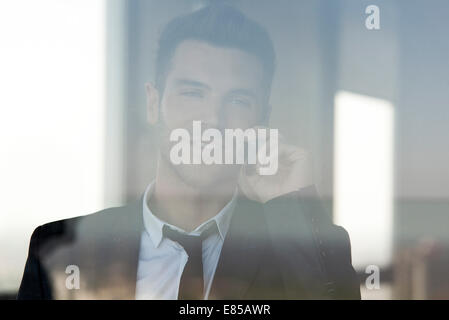 Geschäftsmann, reden über Handy, angesehen durch Fenster Stockfoto