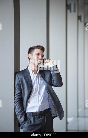 Junger Mann gelehnt Buiding Spalte reden über Handy Stockfoto