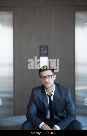 Junge Unternehmer sitzen in Lobby, Porträt Stockfoto