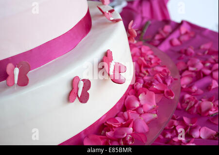 Hochzeitstorte, dekoriert mit Rosenblättern und Schmetterlinge Stockfoto