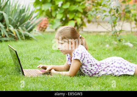 Kleines Mädchen mit Laptop im Garten Stockfoto