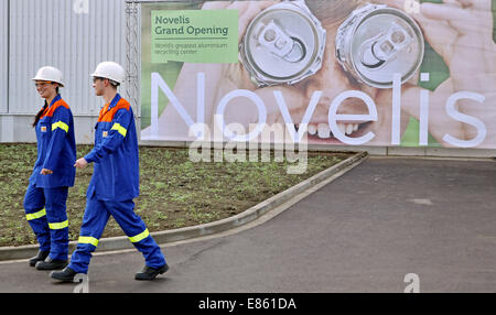 Nachterstedt, Deutschland. 1. Oktober 2014. Zwei Mitarbeiter der Firma vorbeigehen Novelis ein Firmen-Logo auf dem Firmengelände in Nachterstedt, Deutschland, 1. Oktober 2014. Nach Novelis ist es der führende Hersteller von gewalzten Aluminiumprodukten. Novelis eröffnet heute der weltweit größte Aluminium-recycling-Anlage. Das Unternehmen investiert 200 Millionen Euro in das neue Werk. In Zukunft wird es bis zu 400.000 Tonnen Aluminiumschrott verarbeiten und wieder als Aluminium-Barren für das Produktionsnetzwerk. für das neue Werk wurden 200 neue Mitarbeiter eingestellt. Foto: JAN WOITAS/DPA/Alamy Live-Nachrichten Stockfoto