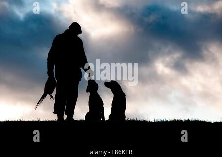 Ein Jäger mit seinen Hunden Silhouetted gegen den Himmel Stockfoto