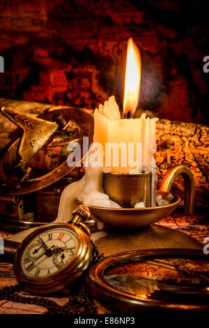 Vintage Compass, Pocket Watch liegen auf einer alten antiken Karte mit eine brennende Kerze Stockfoto