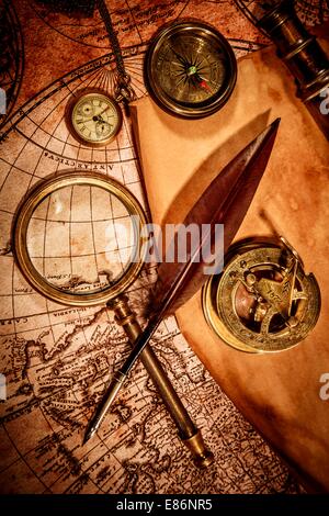 Vintage Lupe, Kompass, Gans Federkiel, Fernglas und eine Tasche sehen Sie liegend auf einer alten Karte. Stockfoto