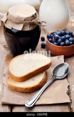 Brot und Blaubeeren Marmelade im Glas auf Holztisch Stockfoto