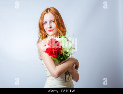 Horizontales Bild der Rotschopf mit Blumenstrauß im Studio auf weiß. Sie Blick in die Kamera Stockfoto
