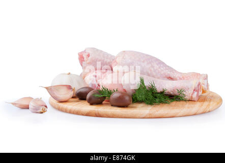 Rohe Hähnchenkeulen mit Oliven und Knoblauch auf einem Holzbrett Stockfoto