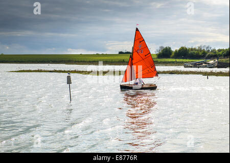 Eine kleine Jolle mit roten Segeln am Fluss Blackwater in Essex. Stockfoto