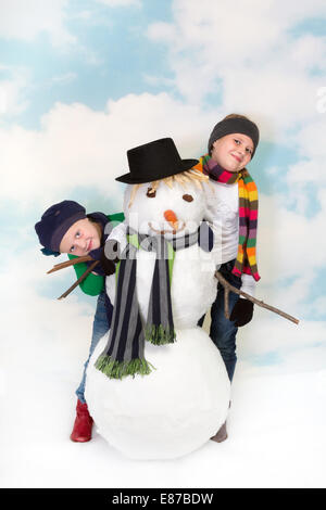 Zwei glückliche Schwestern Herumspielen ihren Schneemann Stockfoto