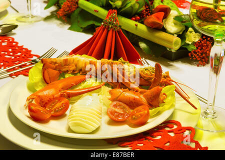 Hummer und Weißwein auf einem festlich gedeckten Tisch mit roten gefaltete Servietten Stockfoto