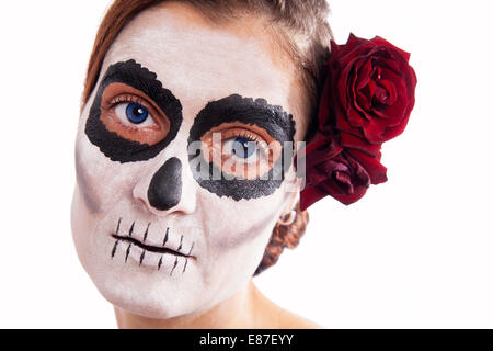 Frau mit Make-up von la Santa Muerte mit roten Rose vor einem weißen Hintergrund Stockfoto