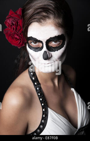 Frau mit Make-up von la Santa Muerte mit roten Rosen vor schwarzem Hintergrund Stockfoto