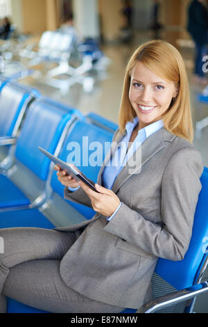 Weibliche Angestellte mit Touchpad Blick in die Kamera während der Sitzung am Flughafen Stockfoto
