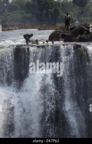 Viktoriafälle, Simbabwe. 2. Oktober 2014.  Ausländische Touristen posieren für Fotos mit lokalen Führern am "Teufels Pool" über die Victoriafälle, an der Grenze zwischen Simbabwe und Sambia, 30. September 2014. Die "Teufels-Pool" ist ein wichtiger Standort für Touristen zu den Victoria Fällen während der trockenen Jahreszeit, vor allem für die Monate September und Oktober, wenn die Wasserstände sind am niedrigsten und der Strom des Sambesi-Flusses ist mild. Bildnachweis: Xinhua/Alamy Live-Nachrichten Stockfoto