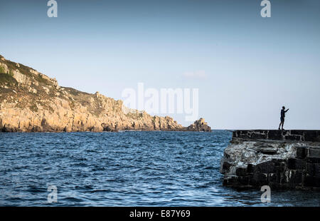 Ein Angler Angeln aus dem beschädigten Kai später Cove in Cornwall. Stockfoto