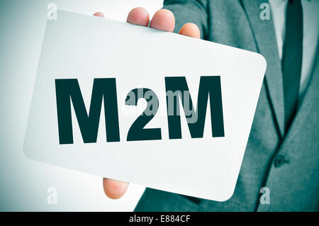 ein Geschäftsmann zeigt ein Schild mit dem Text M2M, für die Technologien von Maschine zu Maschine, geschrieben Stockfoto