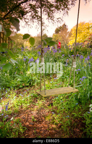 Eine traditionelle Holz- und Seilschaukel hängt von einem Baum in einem East Sussex Landgarten. Stockfoto