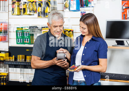 Frau zahlen durch Smartphone im Baumarkt Stockfoto