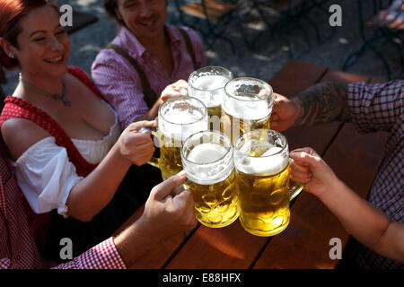 Menschen in traditionellen Kostümen Biertrinken in einem bayerischen Biergarten Stockfoto