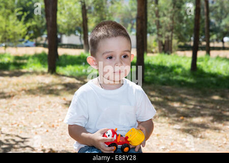 Niedliche kleine Kind Junge spielt mit Spielzeug-Auto im Park an der Natur im Sommer. Verwenden Sie es für Baby, Elternschaft oder Liebe Konzept Stockfoto