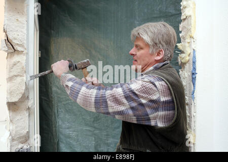 Berlin, Deutschland, arbeiteten Handwerker eine Wand mit Hammer und Meißel Stockfoto