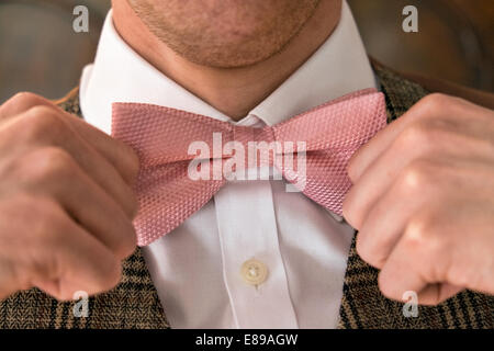 Ein gepflegten Gentleman einstellen Verschärfung seiner rosa Fliege und einen weißen Hemd & Tweed Anzug tragen Stockfoto