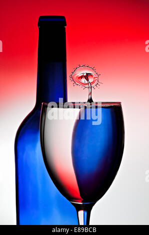 Rot, Weiß und Blau sind, reflektiert und durch Wein Flasche und Glas gebrochen, während ein Wasser Kollision auf der Oberfläche auftritt. Stockfoto