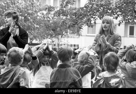 Berlin, DDR, Kindergarten Kinder spielen mit ihren Erziehern im freien Stockfoto